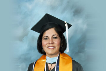 Maria del Carmen Gonzalez - Woman with dark hair wears cap and gown with yellow scarf